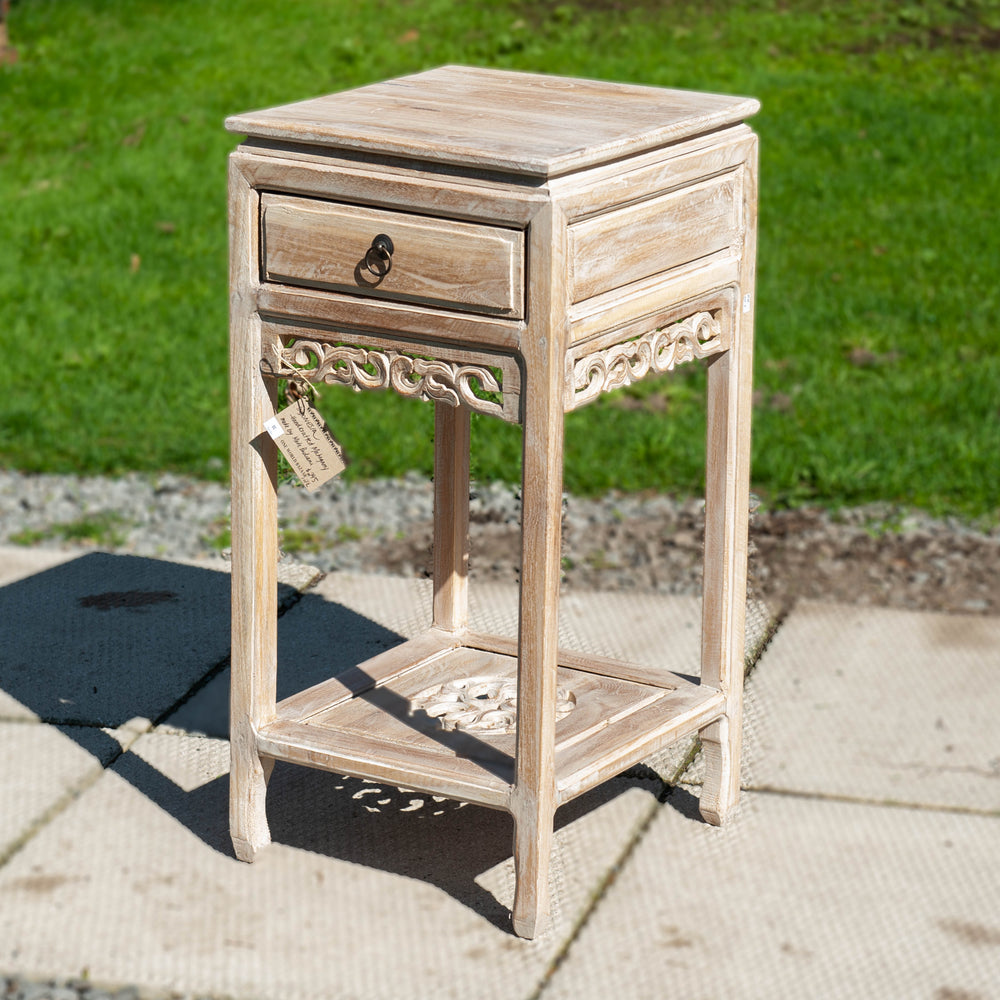 A white side table with ornate carvings and a single drawer