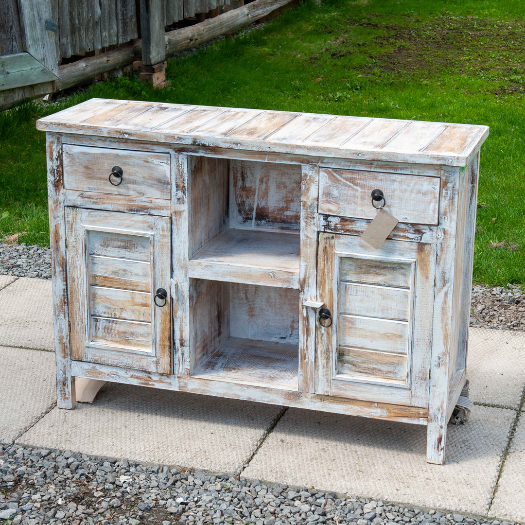 A medium size wooden cabinet in distressed white with 2 doors and storage shelves