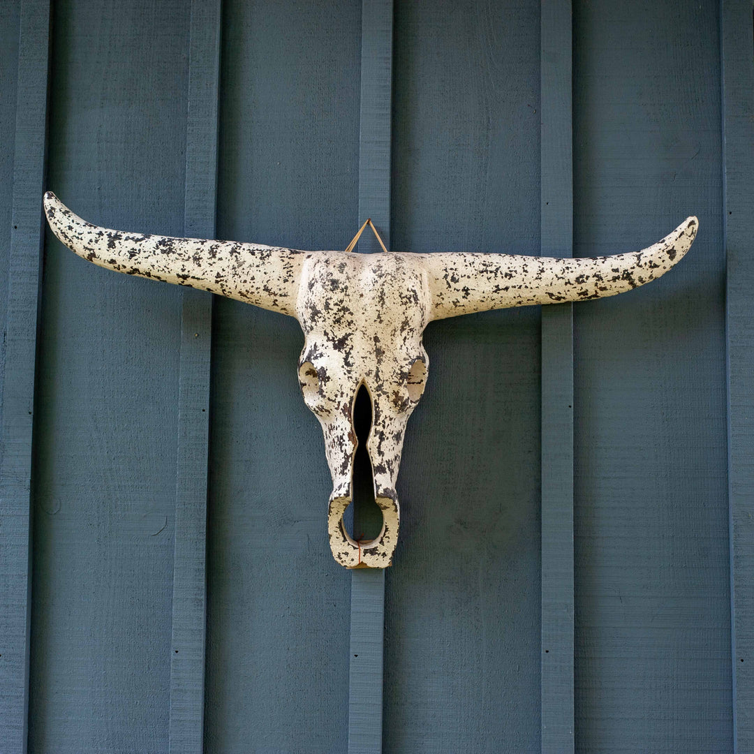 White textured cow skull carved from wood on blue barnboard 