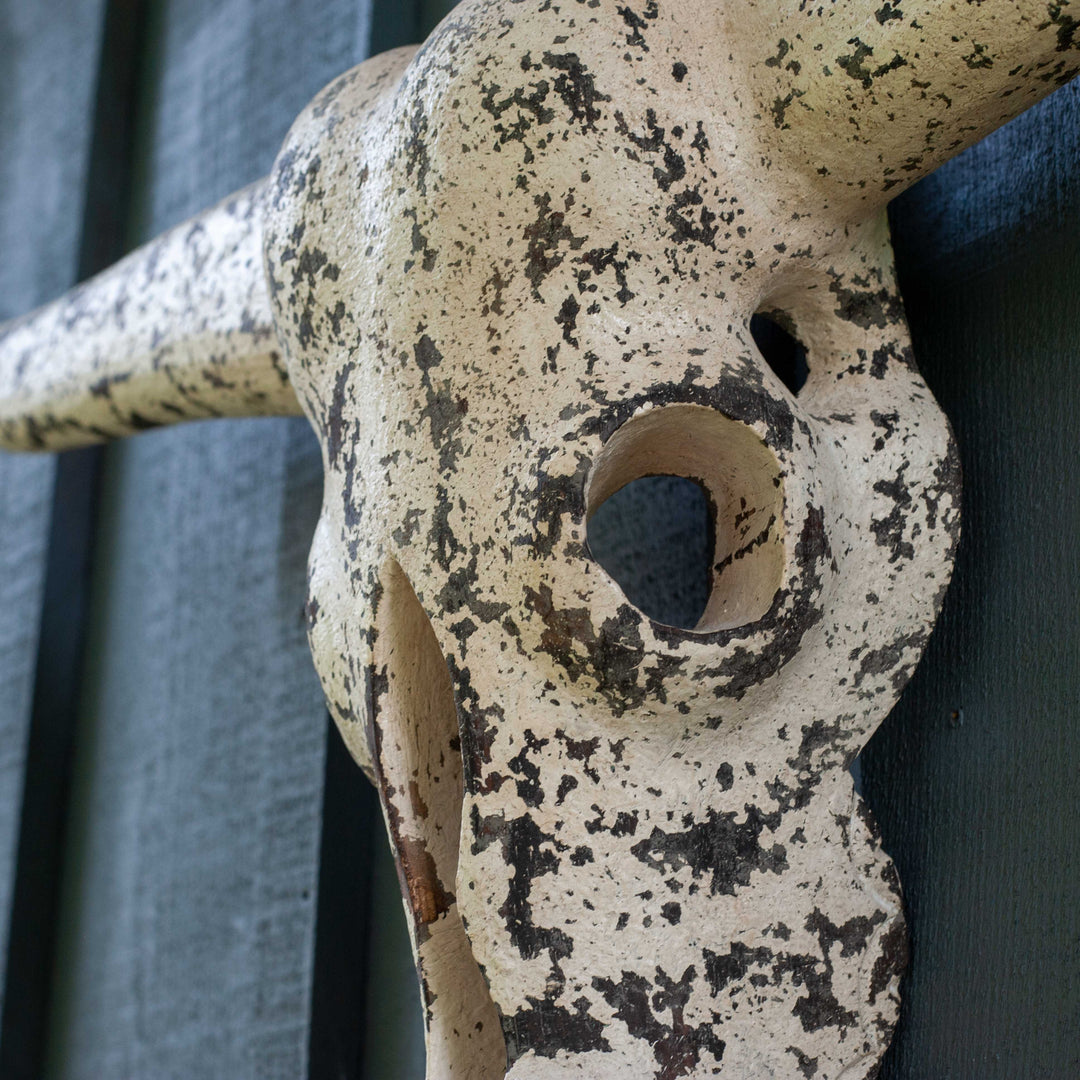 White textured cow skull carved from wood on blue barnboard 