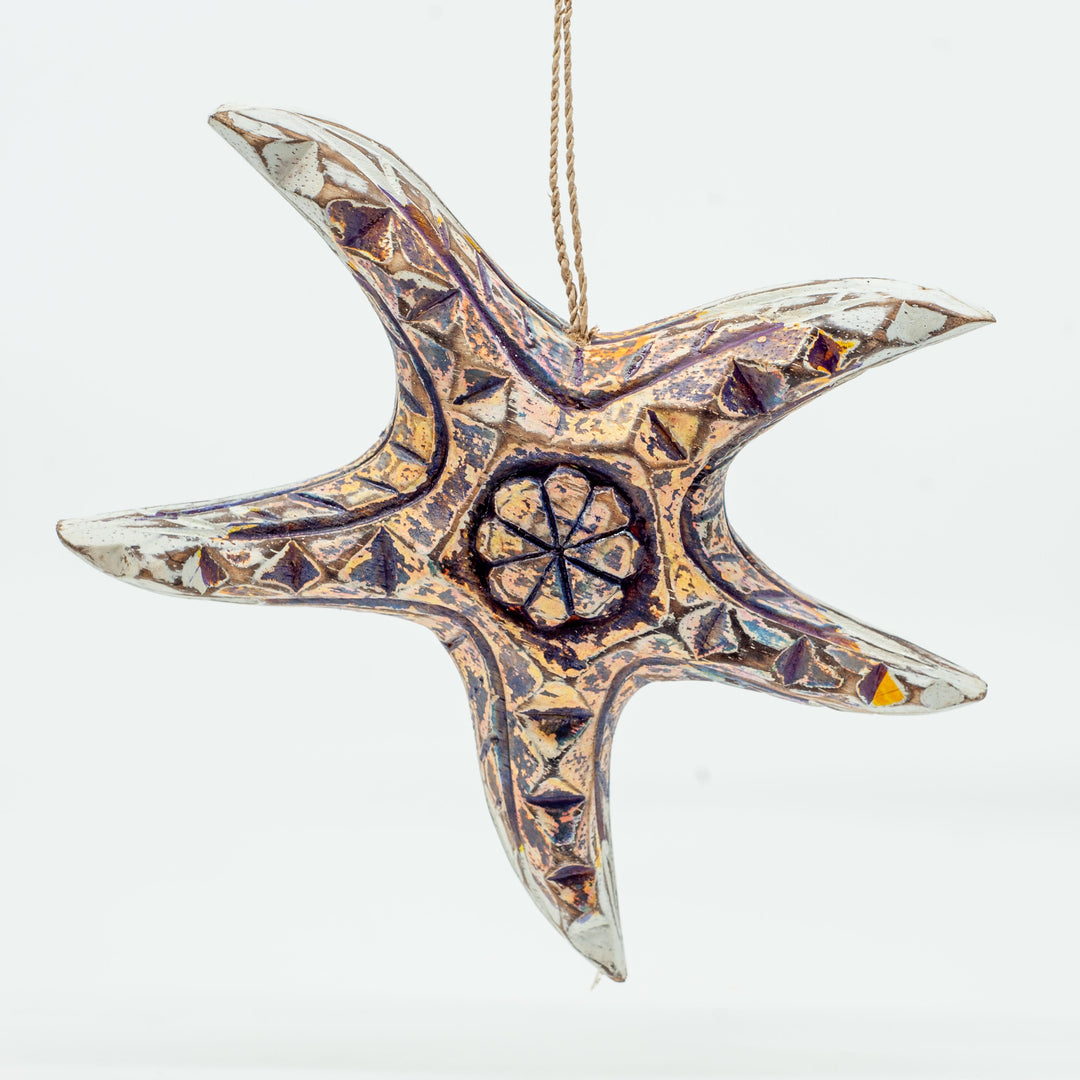 Small driftwood starfish ornament on white background hanging from string. 