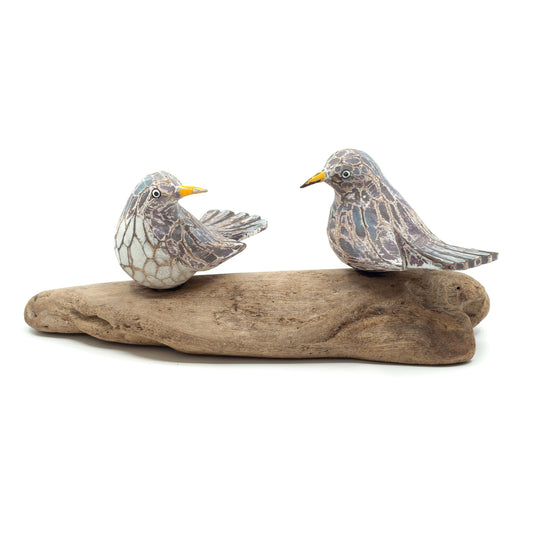 Small driftwood birds on white background on wooden base. 