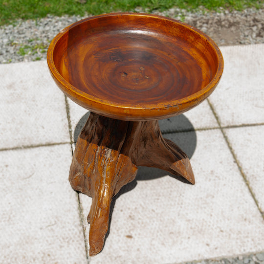 A teak bird bath shaped table on a teak root base