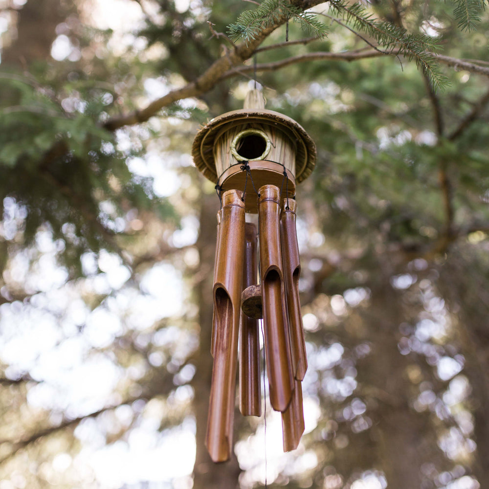 Photo of windchimes with a small grass bird house on top