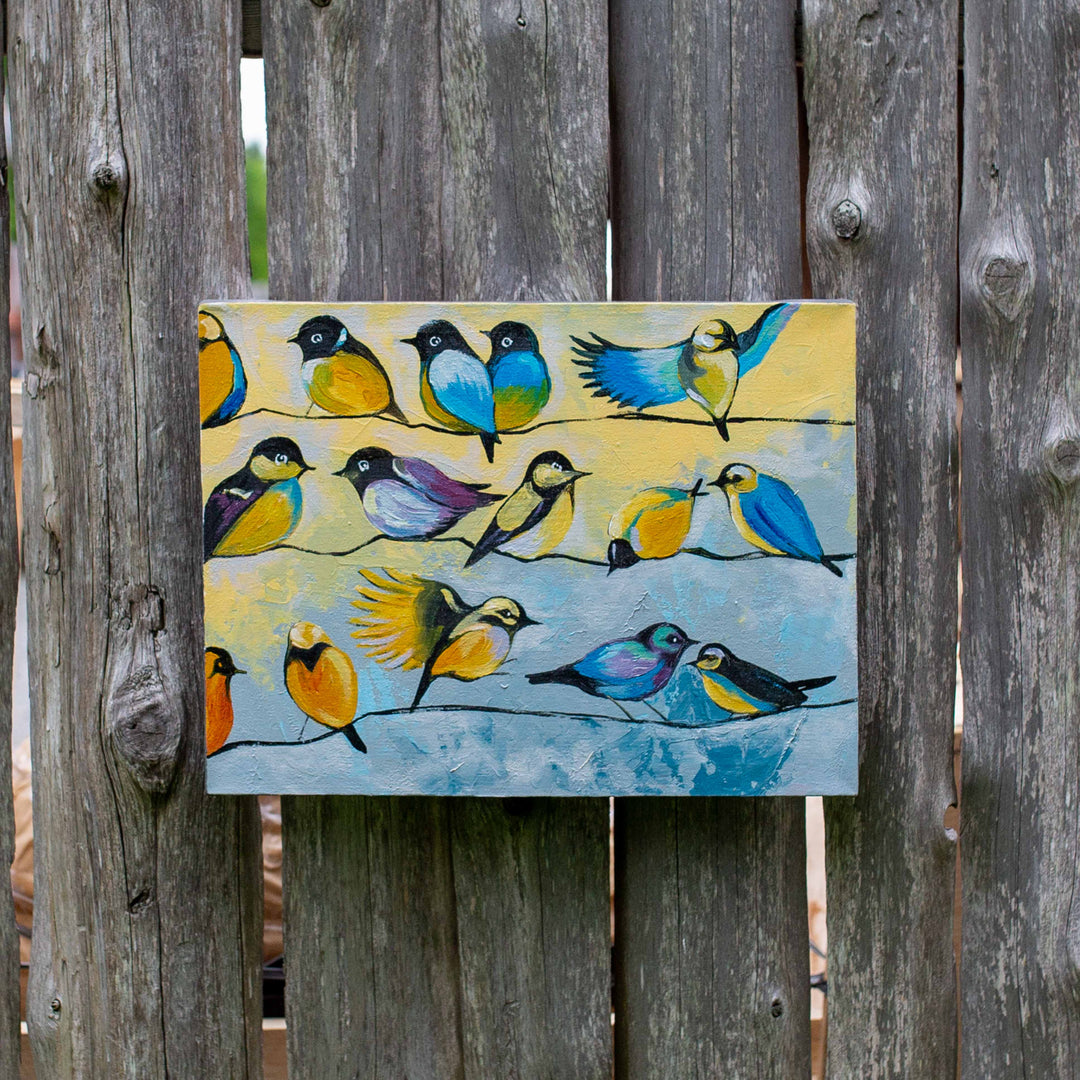 photo of bright song birds, some in flight some sitting on a wire