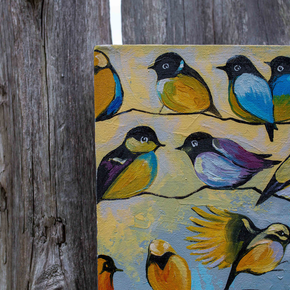 photo of bright song birds, some in flight some sitting on a wire