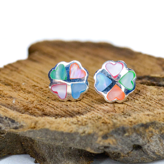 Rainbow coloured silver clover stud earrings on a piece of wood