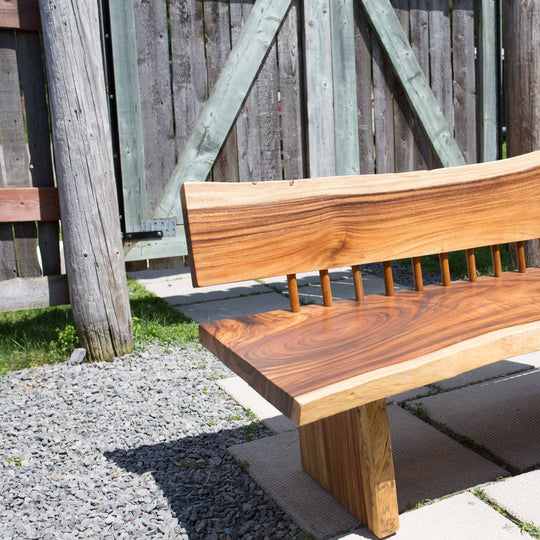 Photo of a sono wood large bench outdoors on a patio against a fence background